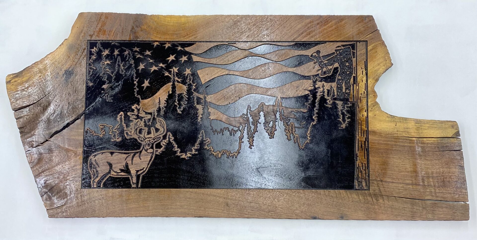 Wooden plaque with forest and deer engraving.