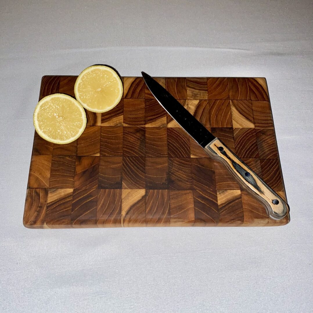 Lemon halves and knife on wooden board.